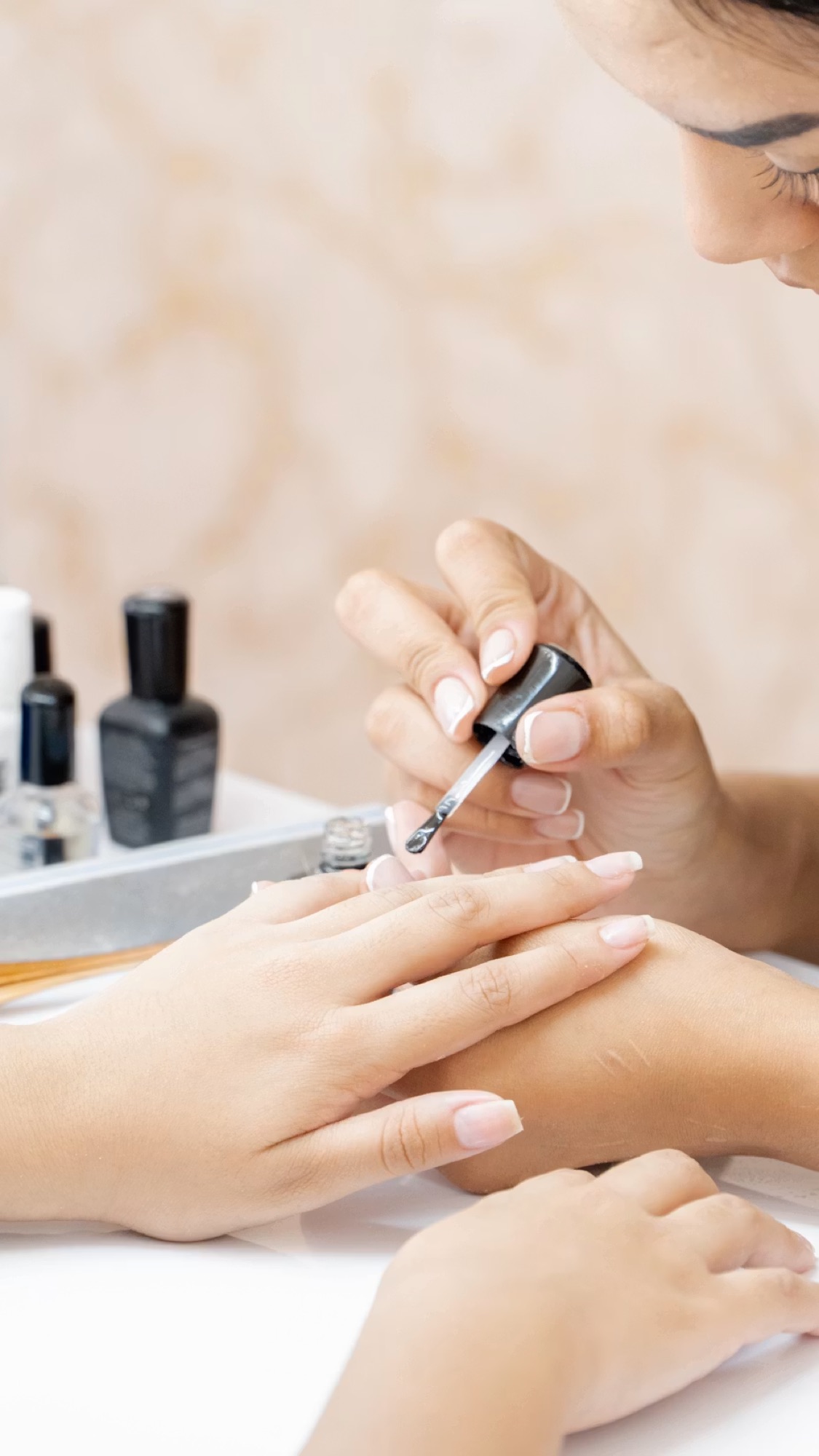 A licensed nail technician applying polish for a client