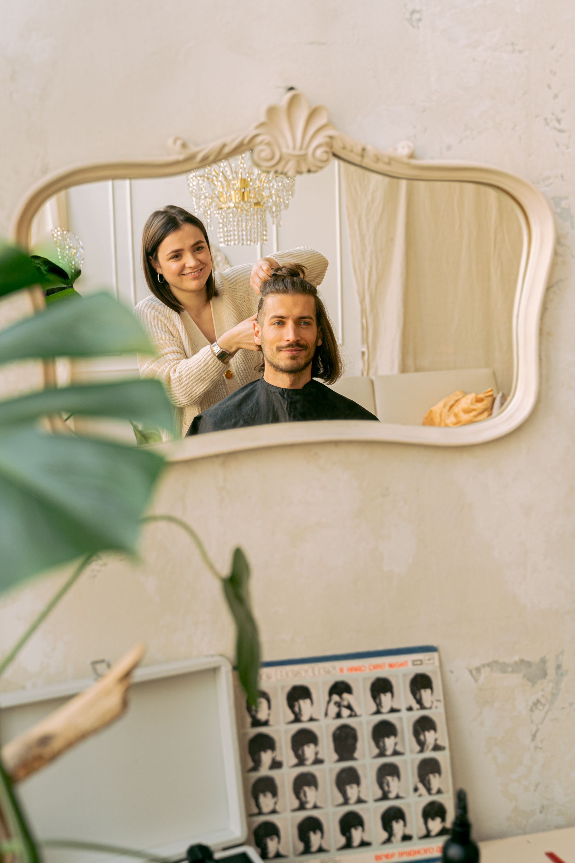 A licensed stylist finishing a client's look, reflected in a salon mirror